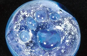 Round blue “calming stone” memorial piece with a paw print and bubble-like accents, featuring ash inclusions.